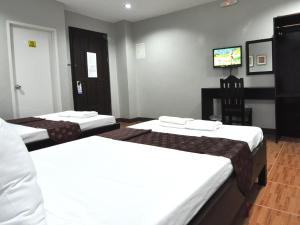 a hotel room with two beds and a flat screen tv at Harbour Gardens Tourist Inn in Tagbilaran City