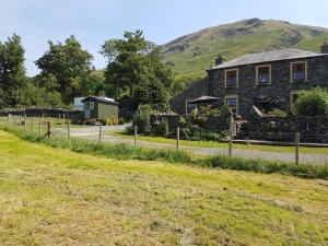 a stone house with a hill in the background at Shepherds hut Dolly wagon in Keswick