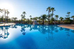 a large swimming pool with palm trees in the background at Puerto Antilla Grand Hotel in Islantilla