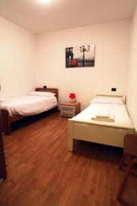 2 Betten in einem Zimmer mit Holzböden in der Unterkunft De La Tour in Tirano