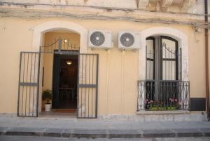 ein Gebäude mit zwei Türen und einem Balkon mit Blumen in der Unterkunft Il Cancelletto in Syrakus