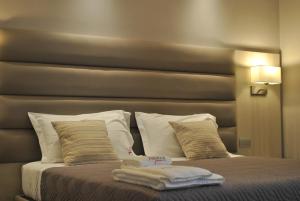 Una cama con almohadas blancas y toallas. en Alludo Aparthotel b&b, en Agrigento