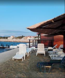 - un groupe de chaises blanches assises sur une plage dans l'établissement Studio apartment Lucija, à Privlaka