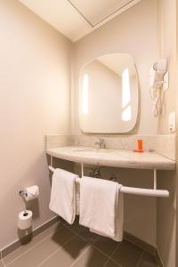 a bathroom with a sink with a mirror and towels at ibis Erechim in Erechim