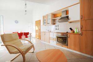 a kitchen with wooden cabinets and a chair in a room at Olea Apartments in Srima