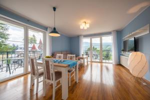 a dining room with a table and chairs and a balcony at RentPlanet- Apartamenty Poezja - Dworcowa in Szklarska Poręba