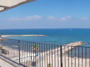 a view of a beach and the ocean from a balcony at Beautiful Apartment on The First Line of The Sea in Haifa