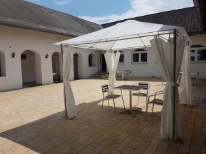 a white tent with chairs and a table in a courtyard at Artemis Farmapartment in Loimeth