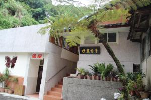 a house with a palm tree in front of it at Qingxiu Hotel in Baihe