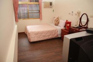 Dormitorio pequeño con cama y TV en Qingxiu Hotel en Baihe