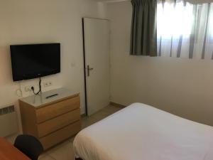 1 dormitorio con 1 cama y TV de pantalla plana en Hotel & Restaurant Heliotel, en Montferrier-sur-Lez