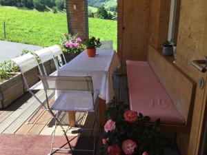 アウ・イム・ブレゲンツァーヴァルトにあるGästehaus Pfandlの花の咲くポーチにテーブルと椅子