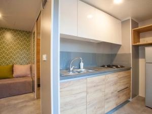 a kitchen with white cabinets and a sink and a couch at Aurora Camping and Mobile Homes in Paralia Panteleimonos