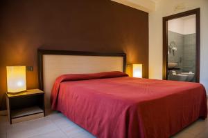 una camera da letto con un grande letto con una coperta rossa di Hotel Il Portico a Favignana Altre 37 foto