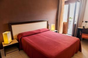 a bedroom with a large red bed and a window at Hotel Il Portico in Favignana