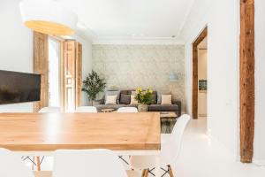 a living room with a wooden table and white chairs at BNBHolder Group Stunning SOL in Madrid