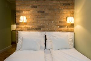 Bett mit weißen Kissen und Ziegelwand in der Unterkunft Roland Apartments in Budapest