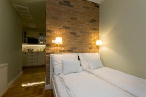 ein Schlafzimmer mit einem weißen Bett mit Ziegelwand in der Unterkunft Roland Apartments in Budapest