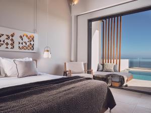 a bedroom with a bed and a chair and a pool at Hotel St.John Suites Adults Only in Tsilivi