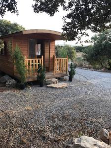 a small wooden cabin with a porch and a driveway at roulotte in Cournonterral