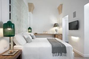 a white bedroom with a white bed and a green lamp at Mantatelurè in Lecce