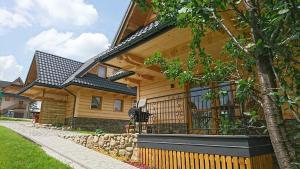 a wooden house with a black roof at Domek SKUPNIOWY UPŁAZ in Murzasichle