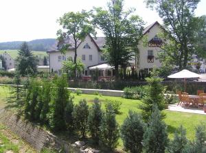 a large white house with a yard with trees at Hotel Bergschlößchen in Pockau