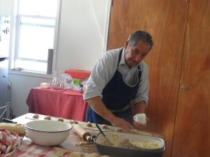 un hombre de pie en una cocina preparando comida en Hostal Santa Fe en Castro