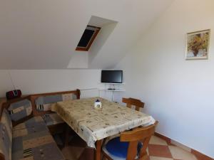 a dining room with a table and chairs and a tv at Bodzavirág Apartman in Hegykő