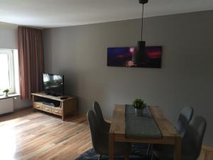 a living room with a dining table and a television at Hafenperle in Tönning