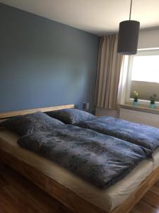 a bed with a blue comforter in a bedroom at Hafenperle in Tönning