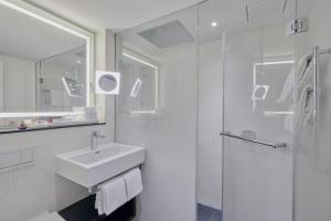 a bathroom with a sink, toilet, and mirror at Sorell Hotel Krone in Winterthur