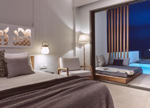 a bedroom with a bed and a couch and a chair at Hotel St.John Suites Adults Only in Tsilivi