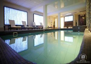 een zwembad met stoelen en tafels in een gebouw bij Strandhotel VierJahresZeiten in Borkum