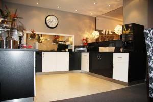 eine Küche mit schwarzen und weißen Schränken und einer Uhr an der Wand in der Unterkunft Hotel Altes Rathaus in Ostfildern