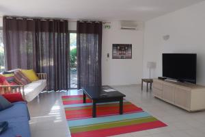 sala de estar con TV y alfombra colorida en Domaine Bocca di Feno, en Bonifacio