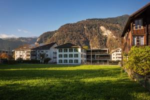 un gruppo di edifici in un campo con montagne sullo sfondo di Independance First a Interlaken