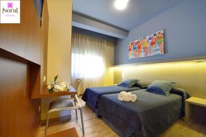 pokój hotelowy z dwoma łóżkami i biurkiem w obiekcie Nuevo Norat Sanxenxo w mieście Sanxenxo