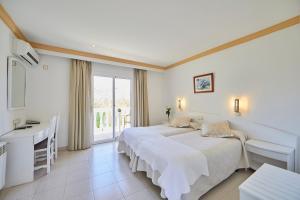 1 dormitorio con cama, escritorio y ventana en Hotel Cupidor en Paguera