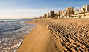 a sandy beach with buildings in the background at Playa Muchavista lovely ground floor apartment in El Campello