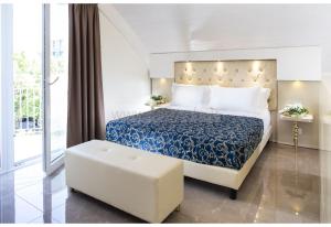 a bedroom with a blue and white bed and a stool at Hotel Ambassador in Rimini