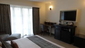 a hotel room with a bed and a flat screen tv at Andores Resort And Spa - Calangute in Calangute