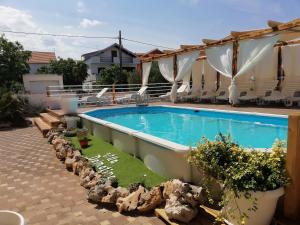 a swimming pool in a yard with chairs around it at Apartments Villa Dalmatina in Vodice