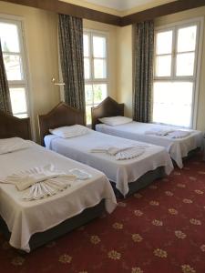 three beds in a hotel room with windows at Antik Ridvan Hotel in Çeşme