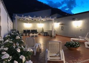 a patio with two chairs and a couch and flowers at NA' SCICCHERIA HOME in Castellammare del Golfo