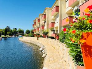 エンプリアブラバにあるPORT SOTAVENT 16A - Apartamento en la Marina de Empuriabrava - piscina comunitaria, - parking - vistas al canal - cerca centro y playaの横に花と建物が流れる川