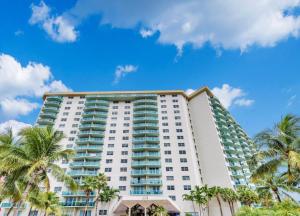 a tall white building with palm trees in front of it at Ocean Reserve Condominium in Miami Beach