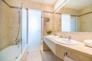 a bathroom with a tub and two sinks and a shower at Hotel Santa Marta in Lloret de Mar