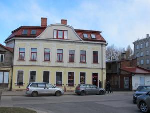 un gran edificio blanco con coches estacionados frente a él en Avanta, en Liepāja