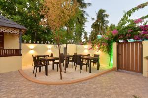 a patio with tables and chairs and a fence at Nala Veli Villa in Ukulhas